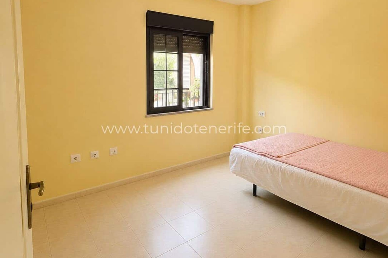 Dormitorio vacío con ventana y paredes amarillas