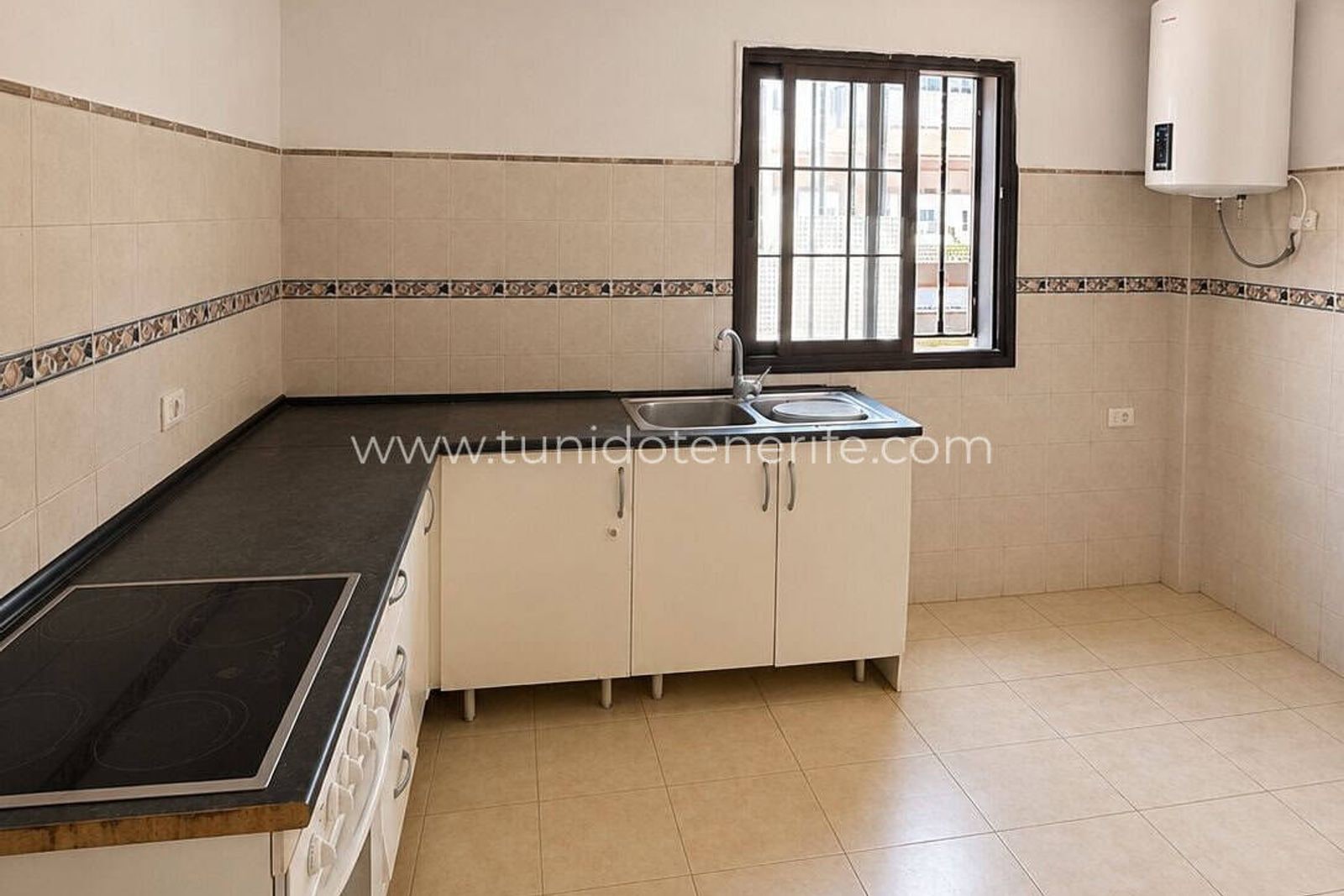 Cocina vacía con encimera negra, fregadero y ventana