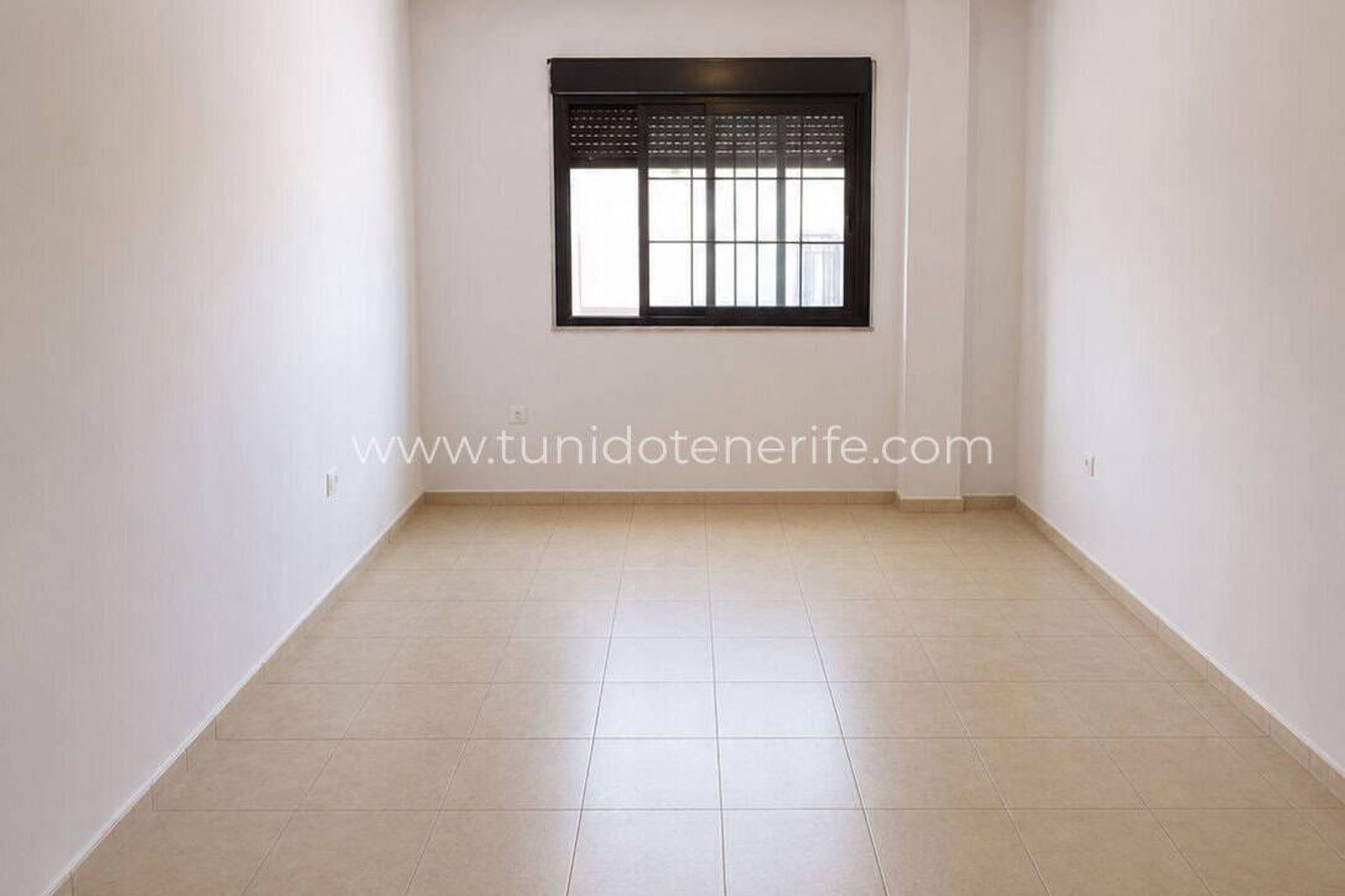 Habitación vacía con suelo de baldosa y ventana